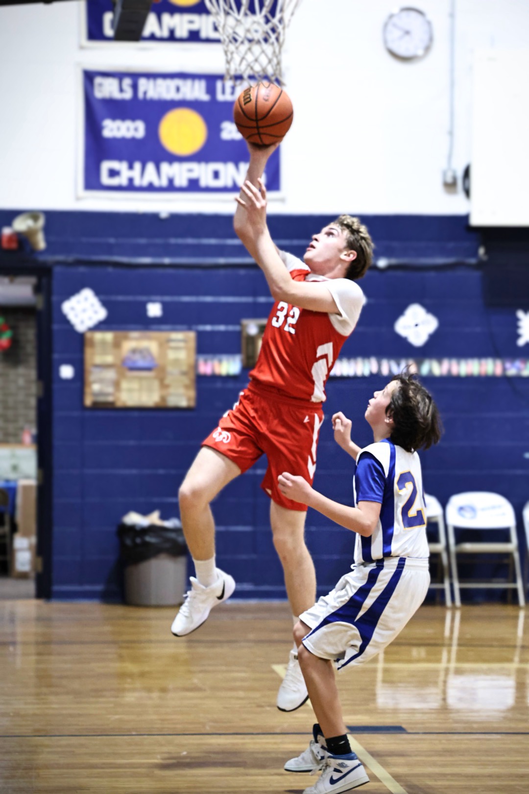 A boy is jersey 32 is midair, laying up into the hoop