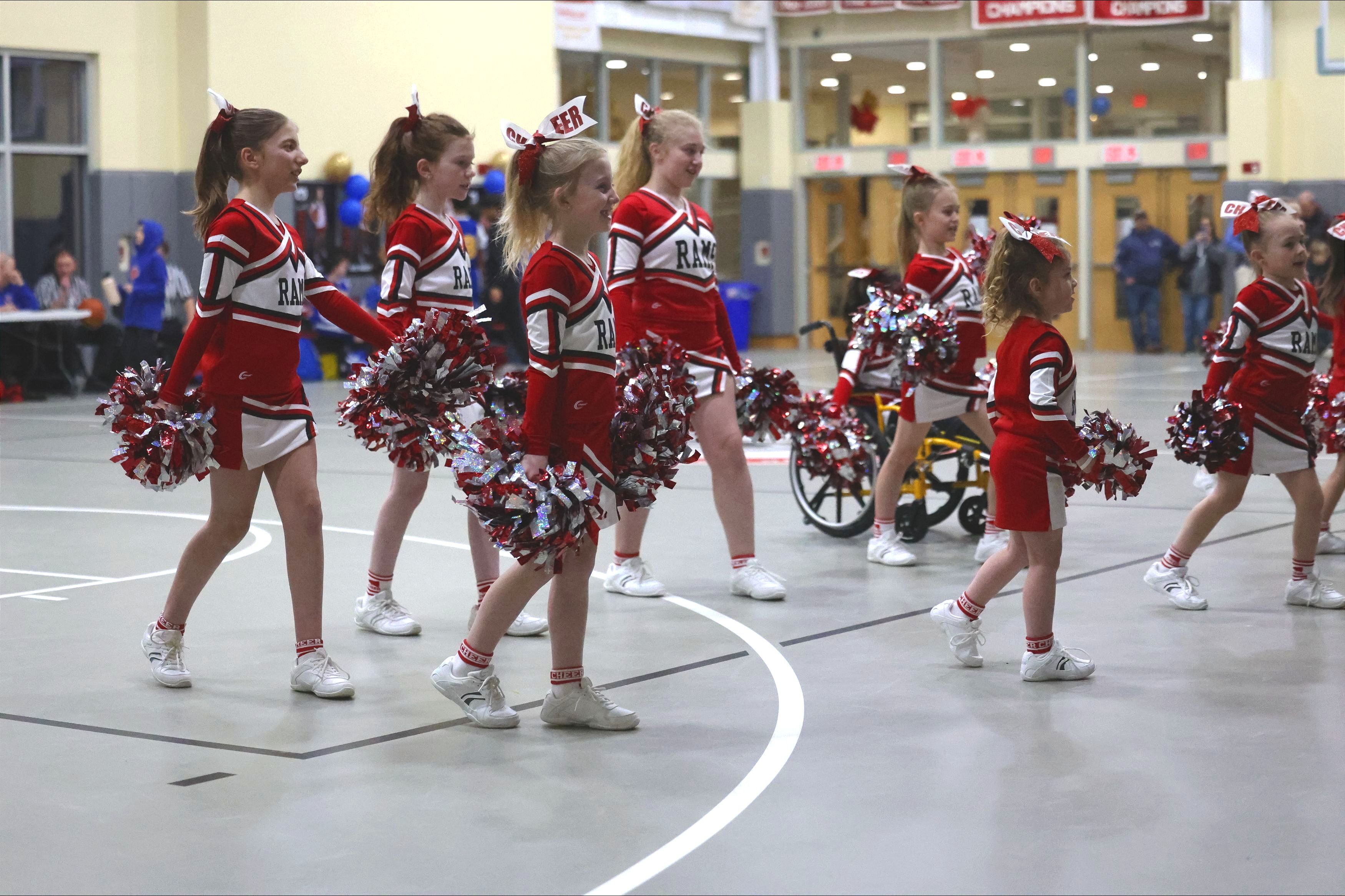 Girls in cheerleading uniforms hold pop poms as they stand in formation