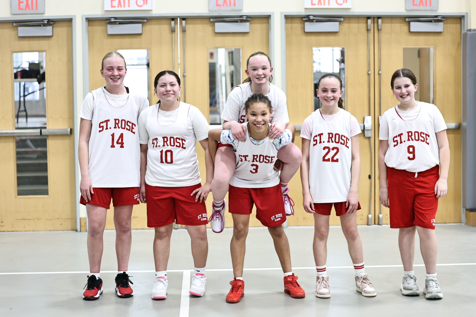 6 middle school schools pose as a team in their basketball jerseys