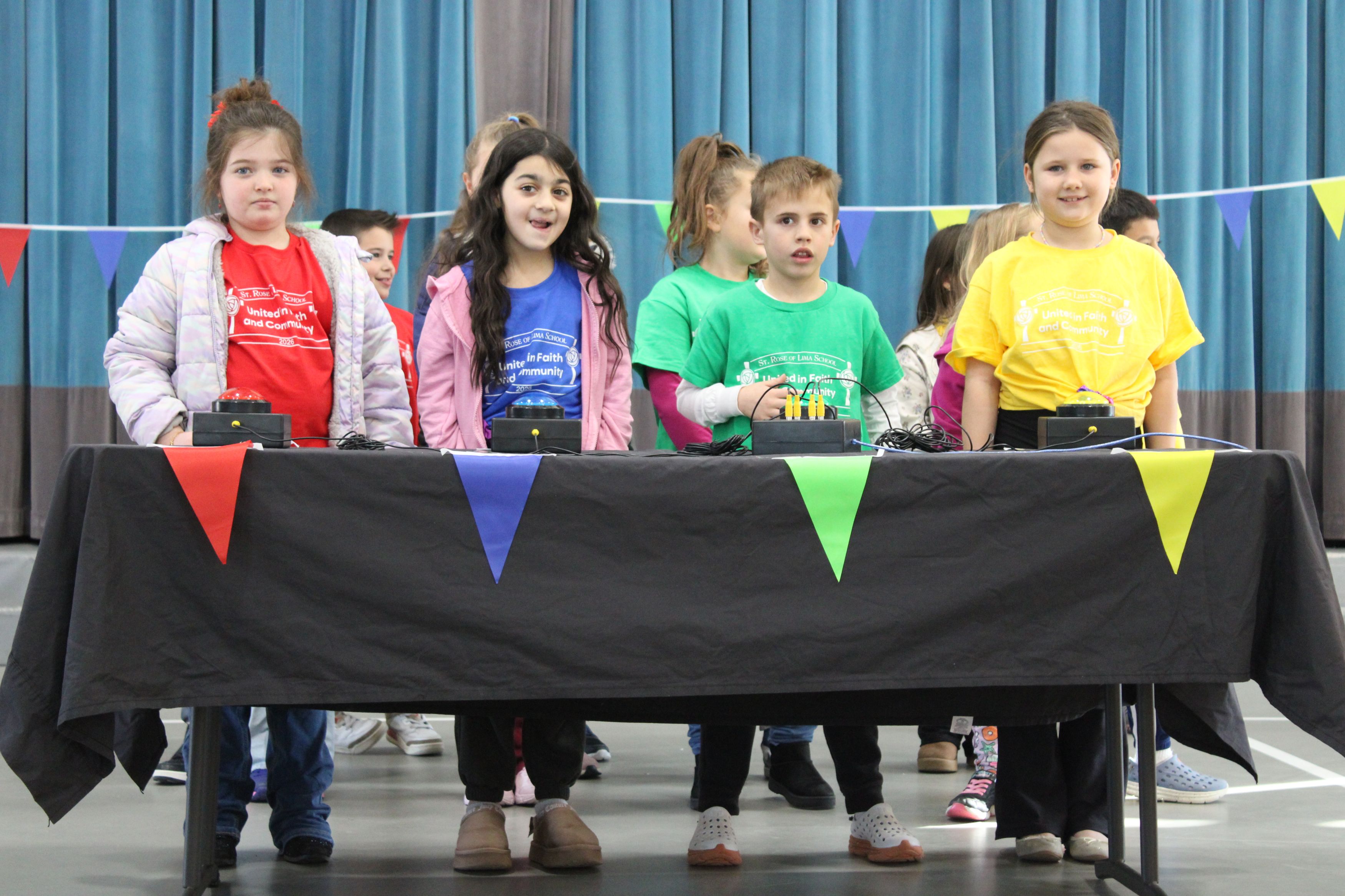 4 students wearing shirts of different colors stand at a table